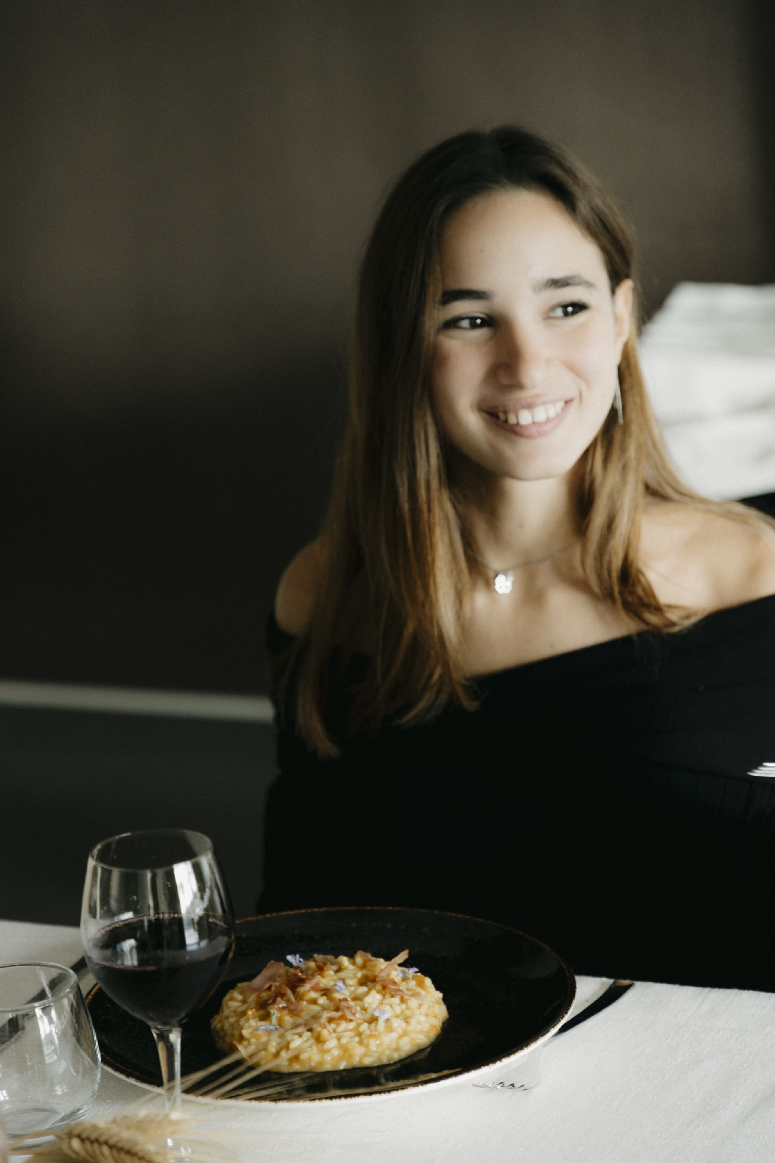 Una ragazza sorridente a tavola con un piatto di risotto
