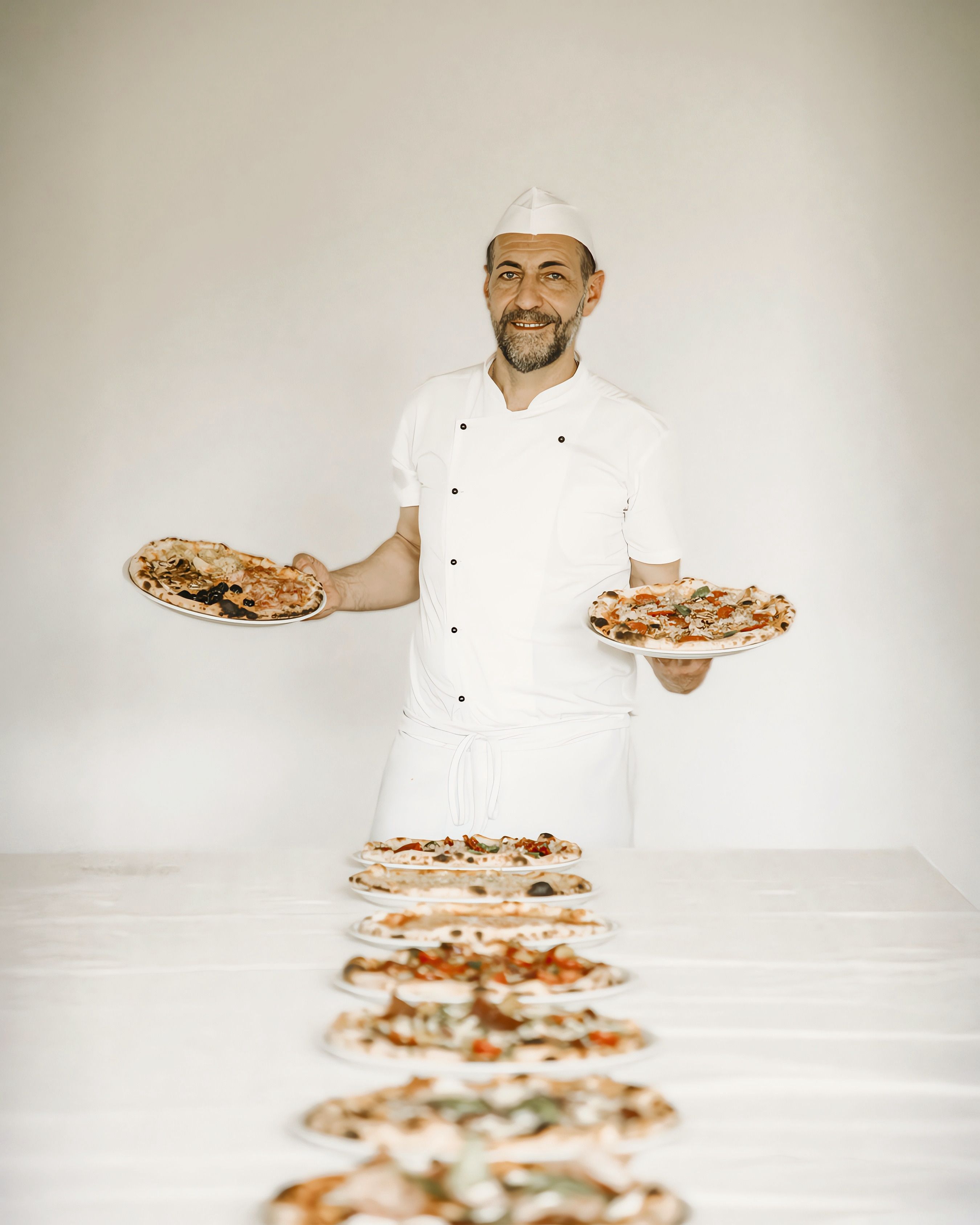 Il pizzaiolo con le pizze appena sfornate in fila