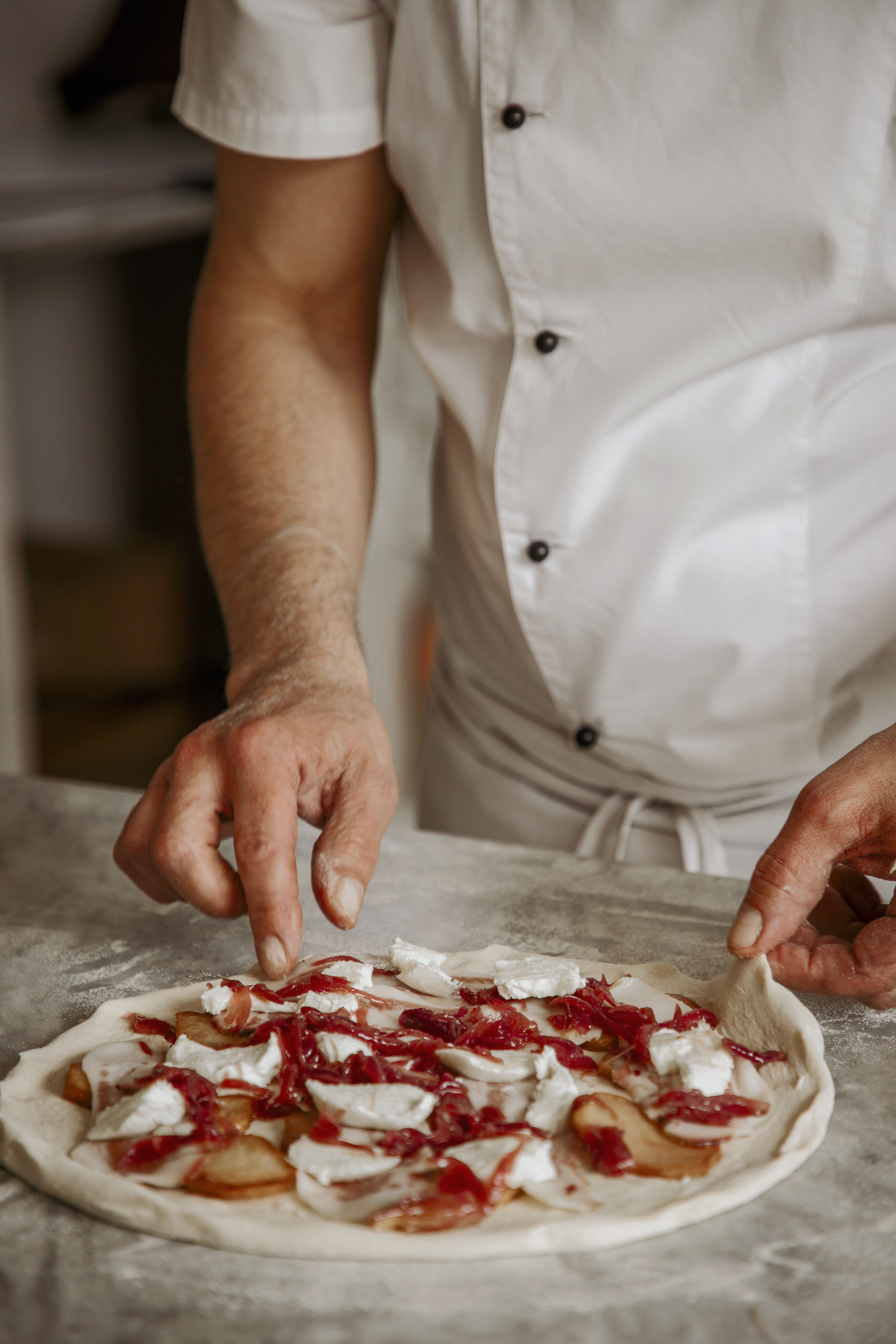 Il condimento steso a mano sulla pizza